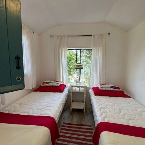 Two twin beds with bright natural light and a view to the water.