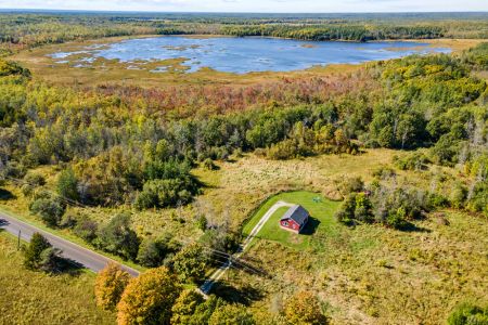 A spectacular aerial view of Smith Homestead with the beautiful waters and wetlands of Ira Lake just beyond the surrounding forest.