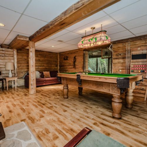 A vibrant games room featuring a billiard table, cozy seating, and warm wood paneling. This space invites friendly competition and relaxed entertainment for all ages.