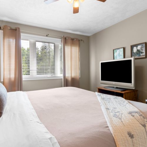 A comfortable bedroom with plenty of natural light and a TV for relaxing at the end of the day.