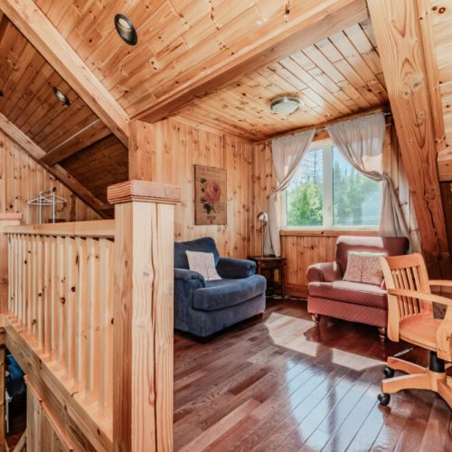 Peaceful loft lounge with cozy armchairs and forest views—ideal for reading, journaling, or enjoying quiet cabin moments.