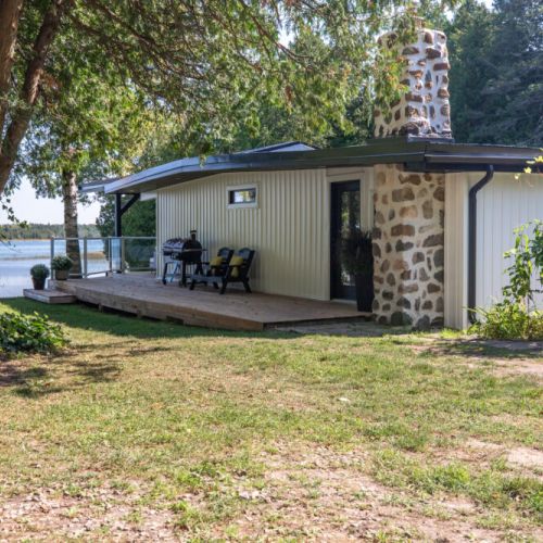 Side view of the cottage with an easy wraparound deck and water just steps away.