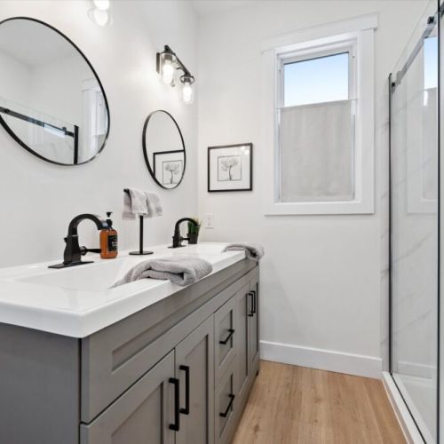 Modern bathroom with glass shower, dual mirrors, stylish fixtures, and a clean spa-like feel.