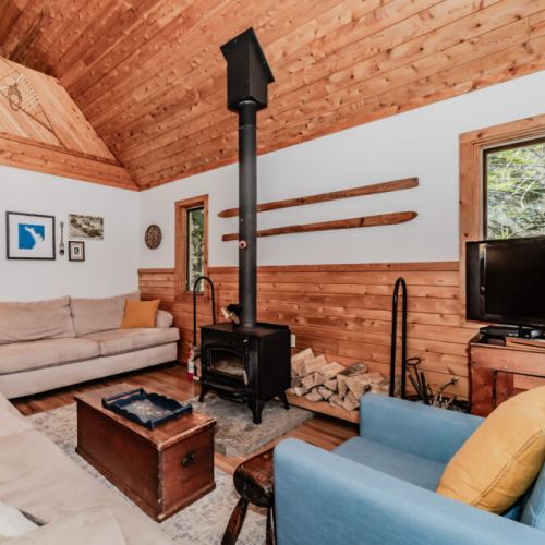 Inviting cottage living area featuring a wood-burning stove, comfy sofas, and rustic charm — ideal for cozy nights by the fire.