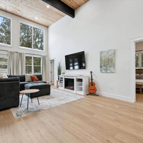 Bright living room with soaring ceilings, large windows, cozy sectional seating, and smart TV.