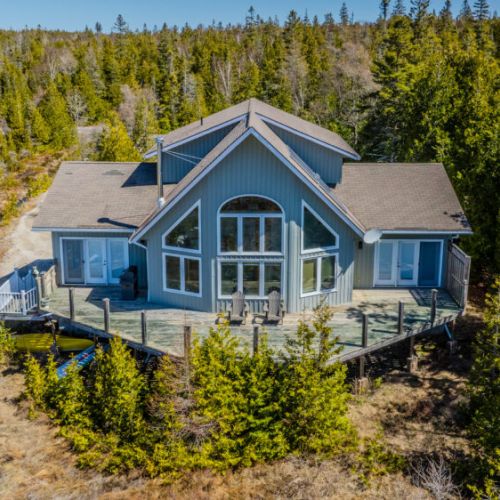 This spacious cottage offers stunning forest views, a wraparound deck, and cozy Adirondack chairs for ultimate outdoor relaxation.