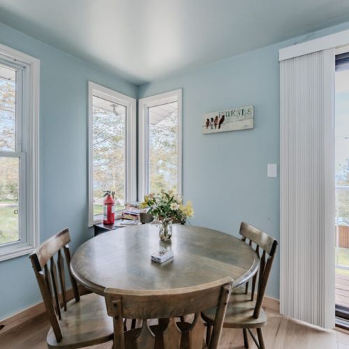 Enjoy your morning coffee or a quiet meal in this quaint breakfast nook, surrounded by windows that offer serene views of the surrounding nature.