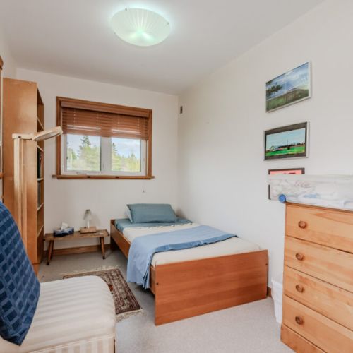 This bright and cheerful bedroom features twin beds and inspiring decor—perfect for kids or friends enjoying a cottage stay near Lake Huron.