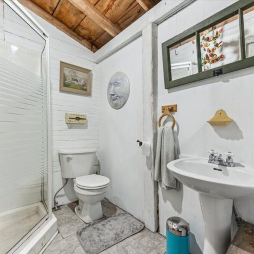Clean, bright, and charming — the main bathroom features a walk-in shower, pedestal sink, and vintage-inspired decor that adds character to your comfort.