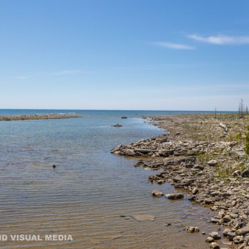 Peaceful lakefront shoreline with shallow crystal-clear water—perfect for exploring and relaxing by the waves.