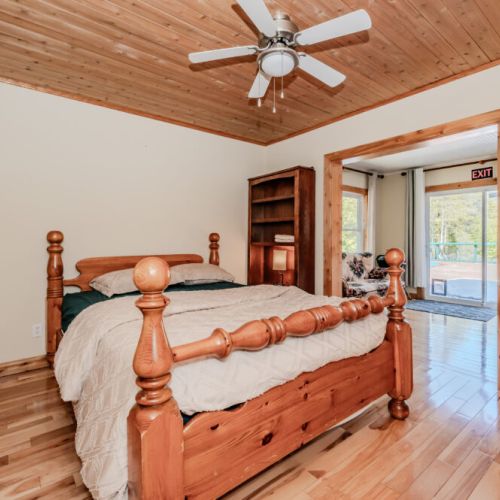 Warm and inviting bedroom with handcrafted log bed, ceiling fan, and natural light—perfect for restful vacation nights.