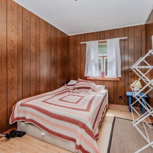 Cozy bedroom with warm wood walls and a plush bed—perfect for a peaceful sleep after a day of exploring nature, hiking, or lakeside adventures.