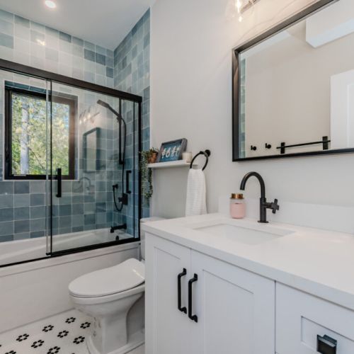 Unwind in style at this vacation rental’s spa-inspired bathroom, featuring a sleek vanity, modern fixtures, and a deep soaker tub with a tiled shower—perfect after a day of hiking, paddling, or relaxing.