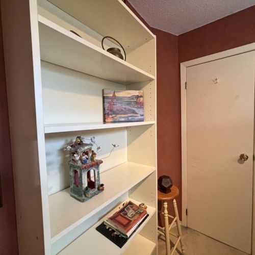 Charming Shelf Display: This delightful shelving unit adds a touch of whimsy to The Louise with its carefully curated ornaments and books. It's a reflection of the cottage's personality, inviting guests to browse through an eclectic mix of reading material or appreciate the charming decorative pieces that make the space feel like a home