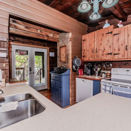 Whip up home-cooked meals in this fully equipped kitchen at a cozy log cabin vacation rental—featuring rustic cabinetry, modern appliances, and direct access to the outdoors. A perfect base for scenic getaways and family-friendly adventures.