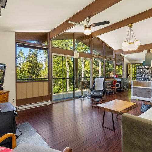 Floor-to-ceiling windows fill the living room with natural light and bring the beauty of the surrounding forest indoors.