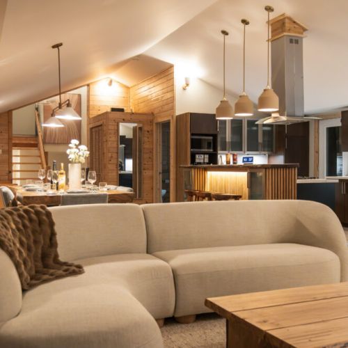 Cozy up in this inviting open-concept living space. Warm wood tones and soft lighting create a relaxing atmosphere. Gather around the fireplace and dining table, or unwind on the plush seating. The perfect space to connect with loved ones.