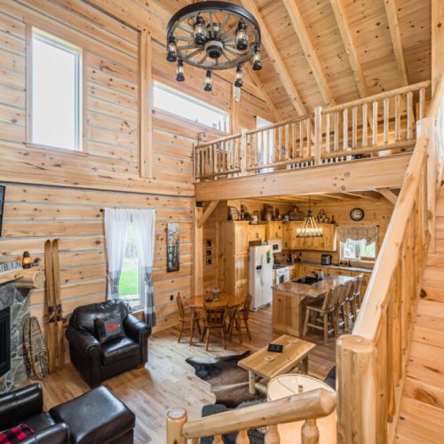 The Great room features comfortable furniture and rustic decor, with a fireplace and TV for warmth and entertainment. The stairway to the loft lounge