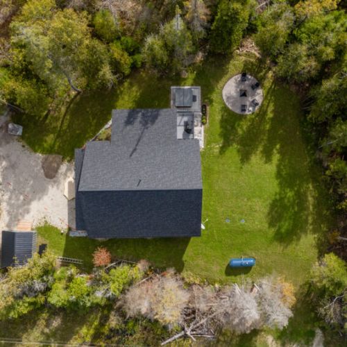 A complete view of the property from above, showcasing the spacious yard, hot tub, and cozy fire pit area.