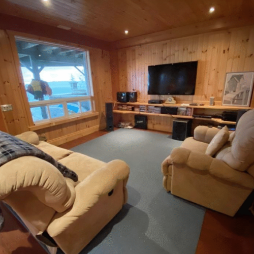 Gather for movie nights or game days in this comfortable entertainment room, featuring plush seating, a large TV, and views of the bay.