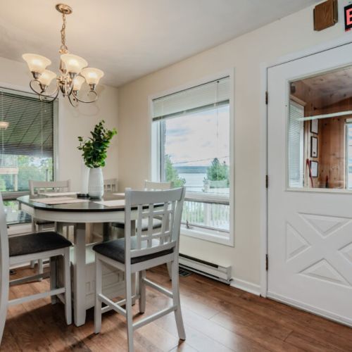 This charming dining space, situated right by the window, offers stunning panoramic views of the lake. Whether you're enjoying a meal or sipping your morning coffee, the natural beauty outside provides the perfect backdrop. The simple yet elegant table setup makes it a delightful spot for any occasion.