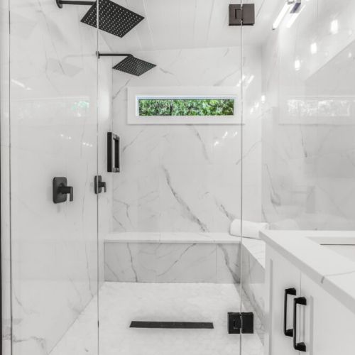 Luxe walk in shower with rain head and bench for rinsing off after lake days.