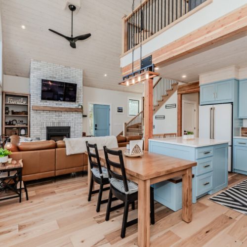 Spacious open-concept vacation rental featuring a designer kitchen, cozy living room with fireplace, and scenic forest views—ideal for family getaways and relaxing retreats near the lake.