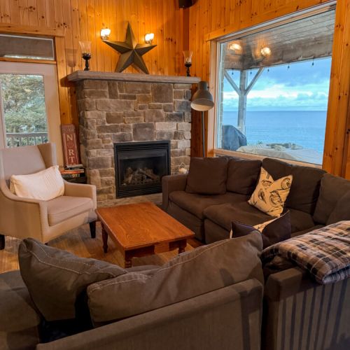 Relax by the stone fireplace with stunning lake views—perfect for cozy evenings, romantic getaways, and unforgettable cottage vacations.