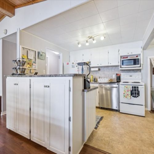 Charming open-concept kitchen with white cabinetry, modern appliances, and a cozy view into the adjoining bedroom.