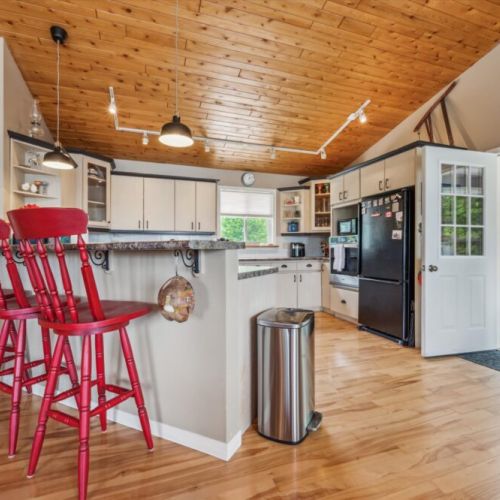 Fully equipped kitchen and bar seating under vaulted wood ceilings—ideal for group meals and morning coffee.