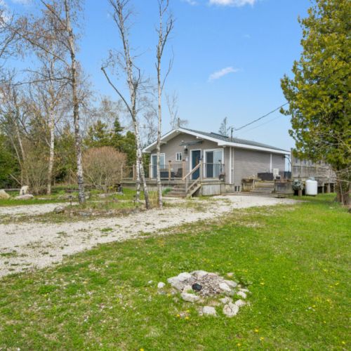 Spacious cottage property with a large lawn, ample parking, and easy access to outdoor living spaces.