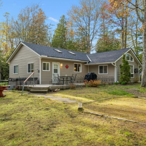 The cottage features easy outdoor living with a spacious deck, patio seating, and plenty of room to gather.