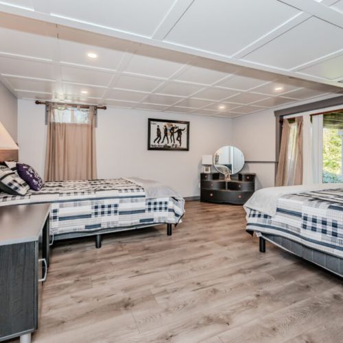 Perfect for families or groups, this spacious guest suite features two cozy beds, forest views, and retro flair—ideal for a relaxed lakeside getaway or extended vacation stay.
