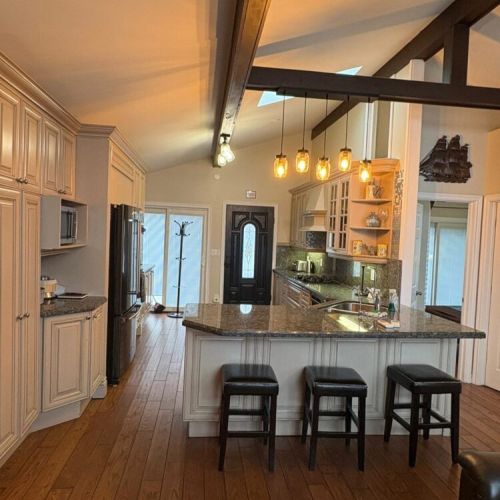 An open-concept kitchen with island seating and warm lighting. A central gathering space for entertaining, dining, and memorable cottage vacations.