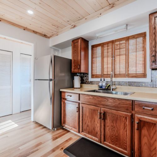 Plenty of kitchen counter space kitchen featuring a modern fridge and sink with a window that looks out to the serene outdoors.