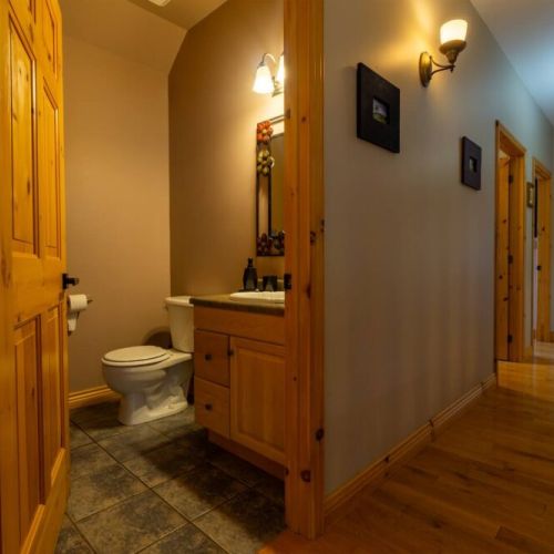 Conveniently located half-bath along a charming wood-accented hallway—adding function and comfort to your cottage getaway.