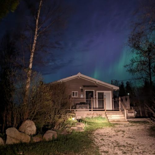 Sunset Cove illuminated under the Northern Lights — the perfect welcome to your lakefront getaway.