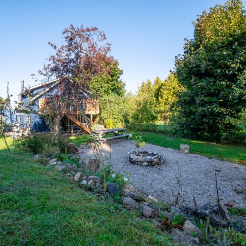 Gather around the fire pit for cozy evenings under the stars, complete with a picnic table and lush surroundings.