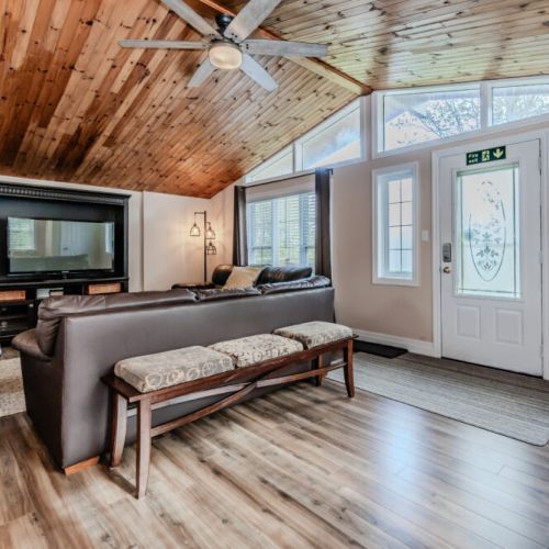 Relax in the airy living room, where vaulted wooden ceilings and large windows create a bright and welcoming atmosphere.
