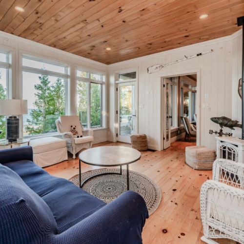 This charming sunroom features rustic decor with a cozy stove, natural wood accents, and French doors leading to a bright, relaxing space.