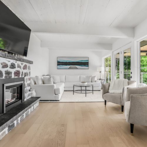 Bright open-concept living room with a comfy sectional, stone fireplace, and beautiful bay views.