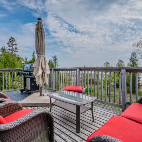 Relax on the upper deck surrounded by trees and fresh air, with stylish seating and views of Lake Huron—perfect for sunset lounging.