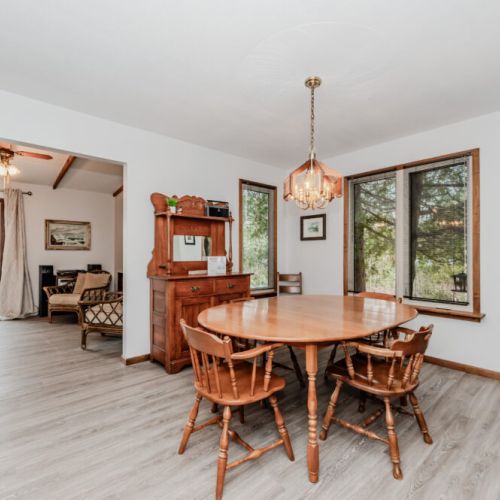 Bright dining room with wood furnishings and water views, ideal for cottage breakfasts or sunset dinners.