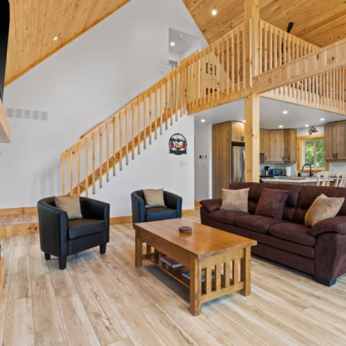 The bright living area features soaring cathedral ceilings and cozy seating around the fireplace.