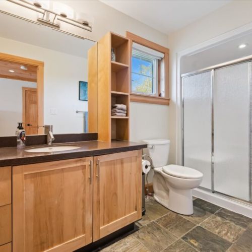 Modern bathroom with walk-in shower and beautiful natural wood cabinetry.