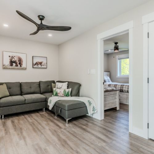 This family room offers a comfortable seating area with a sectional sofa, perfect for relaxing. Located in the upper loft, the room is decorated with nature-themed artwork and has a modern ceiling fan.