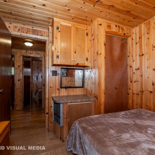 Rustic charm throughout — bedrooms open into the warm wood-lined hallway and common space.