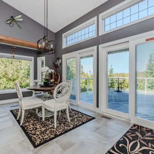 Chic dining nook with panoramic forest views and direct access to a spacious outdoor deck—perfect for morning coffee or sunset dinners during your peaceful vacation stay.
