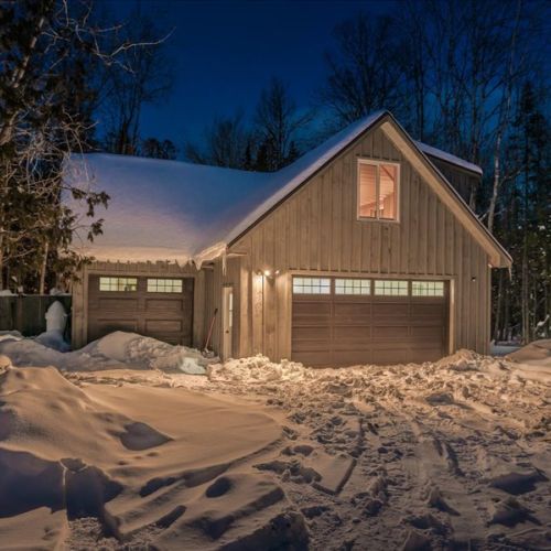 The loft suite sits above the heated garage, offering a private and independent stay surrounded by nature. Warm lighting and snowy evenings make it feel extra cozy in winter.
