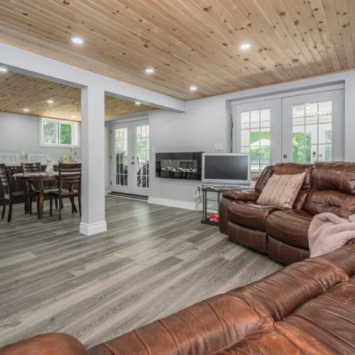 Lower level lounge with TV and Chromecast, exits to the mud room. It features a games table, ambient fireplace and kitchenette.